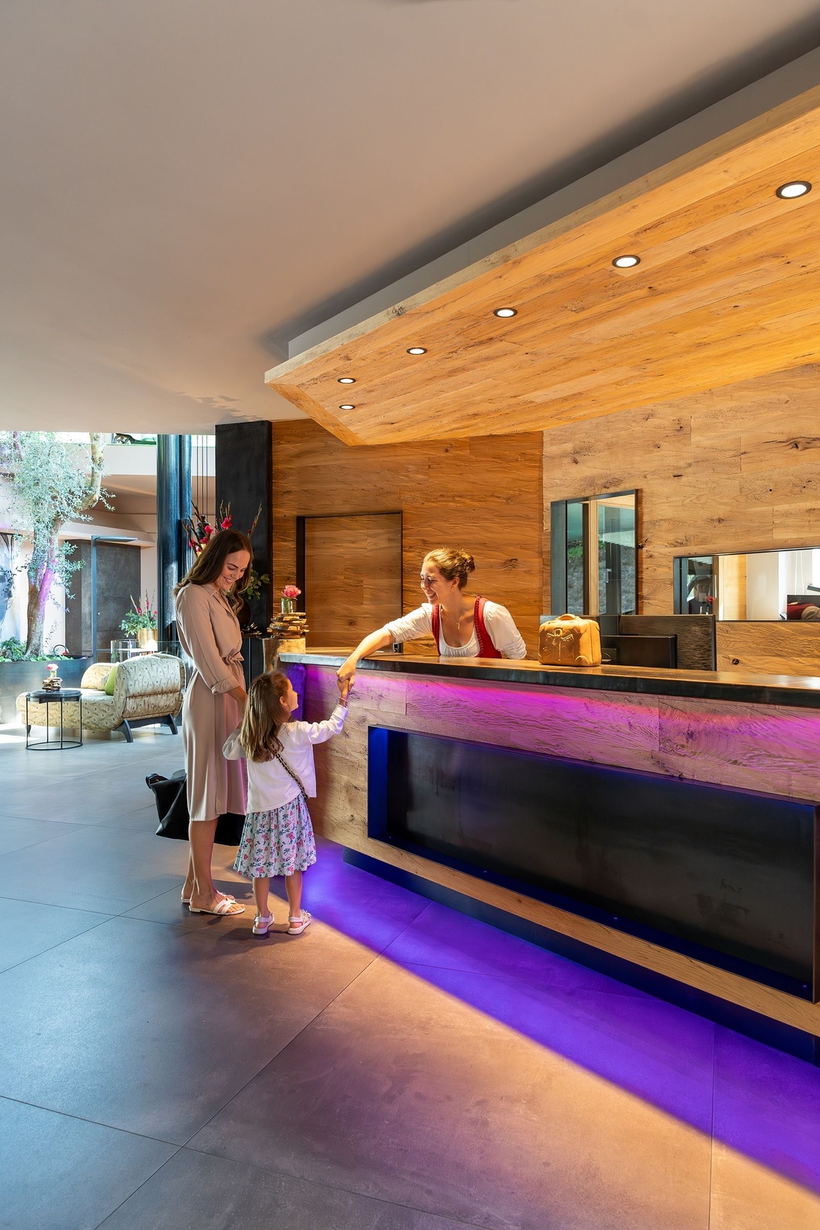 nette Dame der Rezeption begrüßt eine Familie im Familienhotel Südtirol
