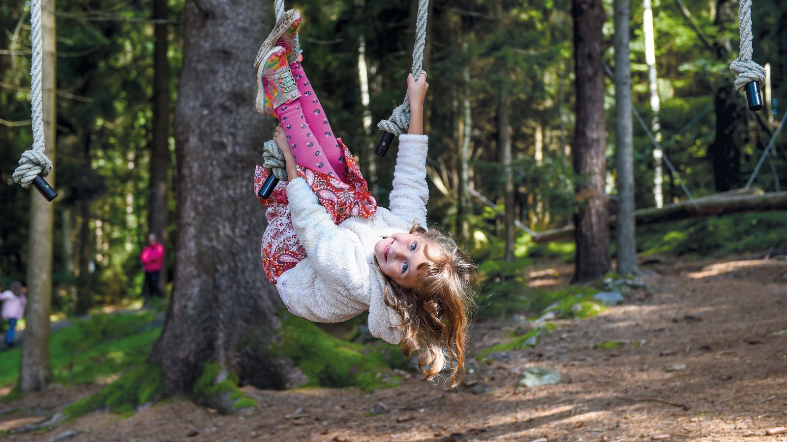 Mädchen klettert im Waldspielplatz an Seilen