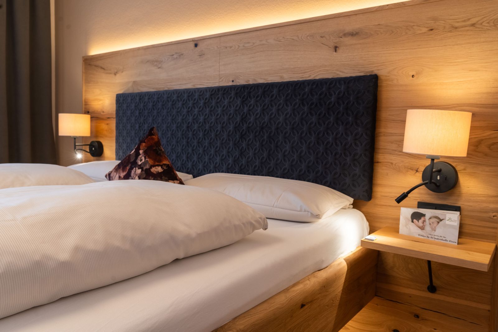 Doppelbett in Nahaufnahme vom Doppelzimmer Heimatglück im Wellnesshotel Eggensberger mit Kissenmenü-Flyer