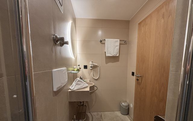 Badezimmer des Einzelzimmers "klein aber fein" im Wellnesshotel mit Spiegel, Waschbecken, Toilette und Dusche