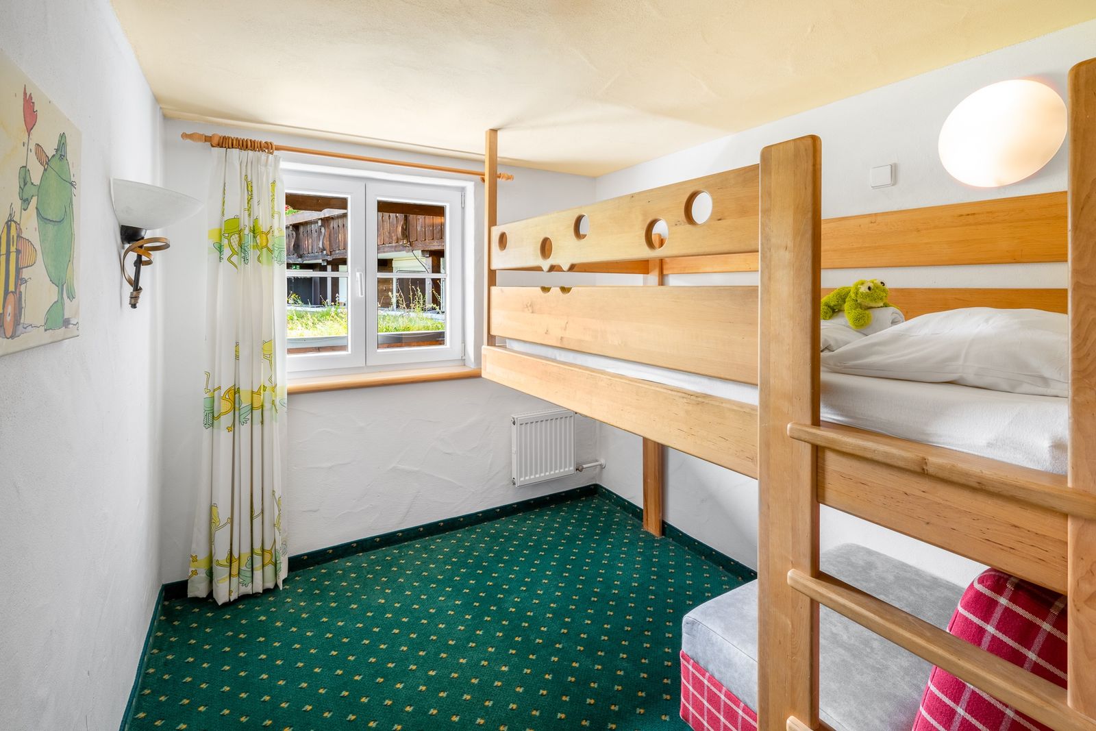 Kinderhotel Allgäuer Berghof – Kinderzimmer Familiensuite Froschkönig mit Blick auf die Allgäuer Alpenche Familiensuite mit Wohn-Schlafraum für die Eltern. Kuscheliges Kinderzimmer mit Hochbett und darunter liegendem ausziehbarem Sofastuhl und beeindruckendem Bergblick.