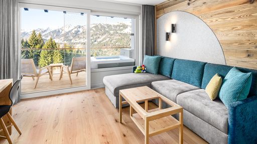 Kinderhotel Allgäuer Berghof – Wohnzimmer Familien-Suite Spass-Suite Froschi mit Blick auf die Allgäuer Alpen