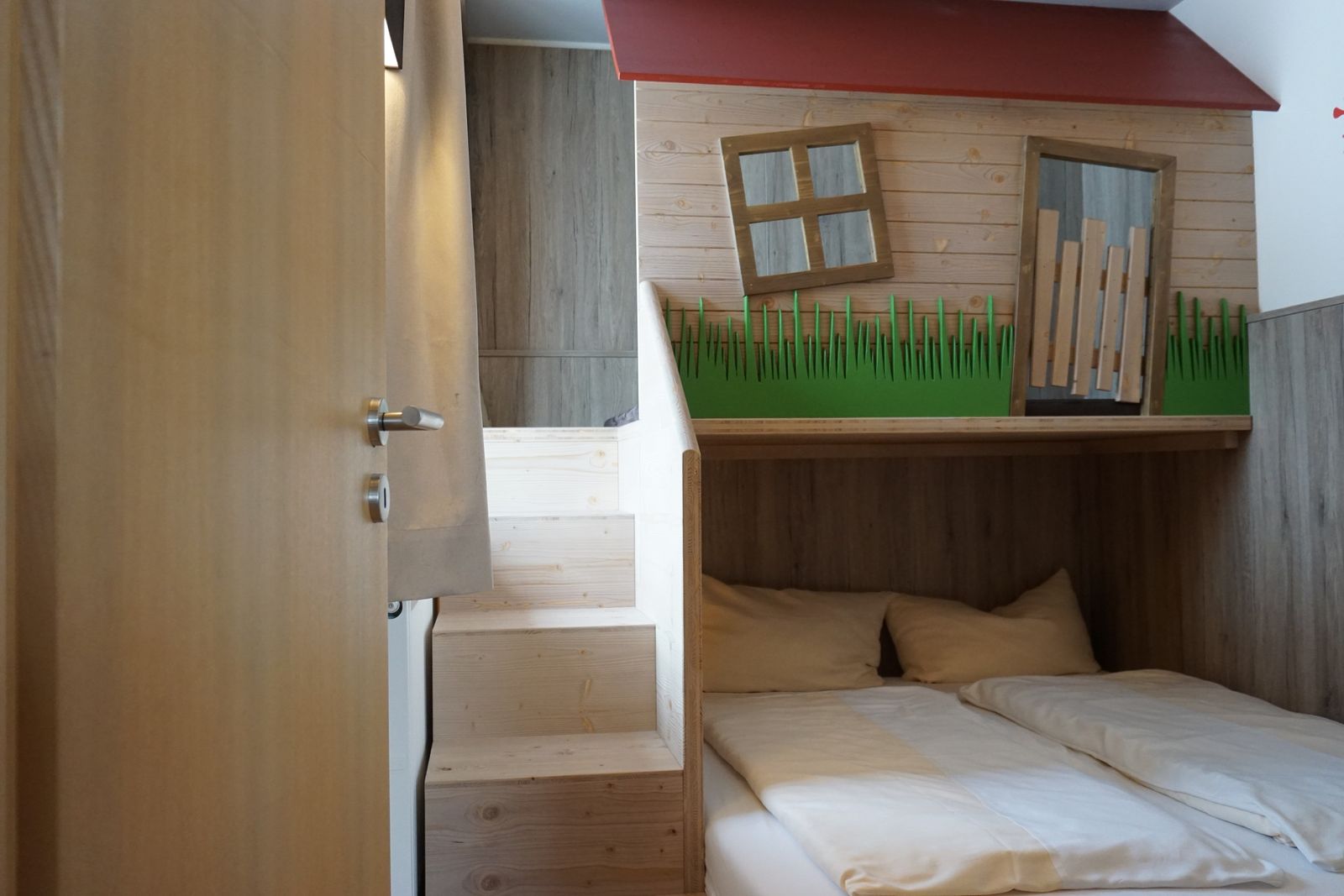 Kinderzimmer mit Doppelbett, darüber ein kleines Spielhäuschen