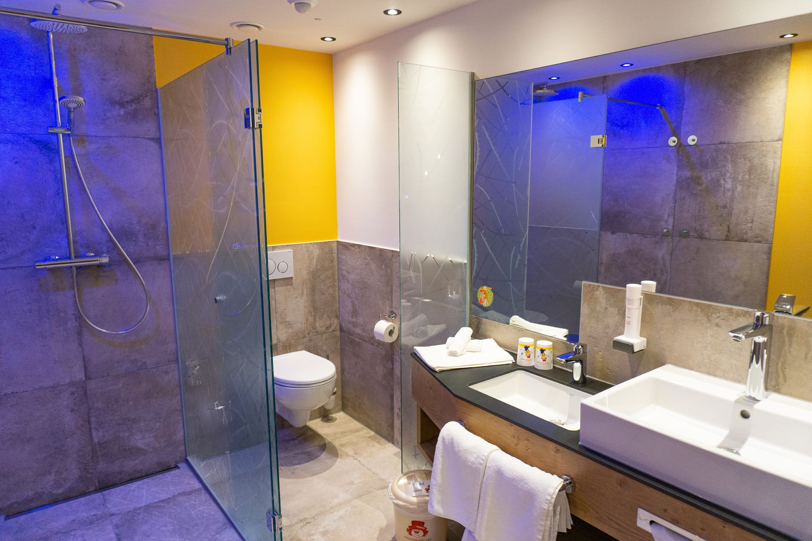 Badezimmer mit Dusche und Toilette, 2 Waschbecken, eines davon niedriger für Kinder