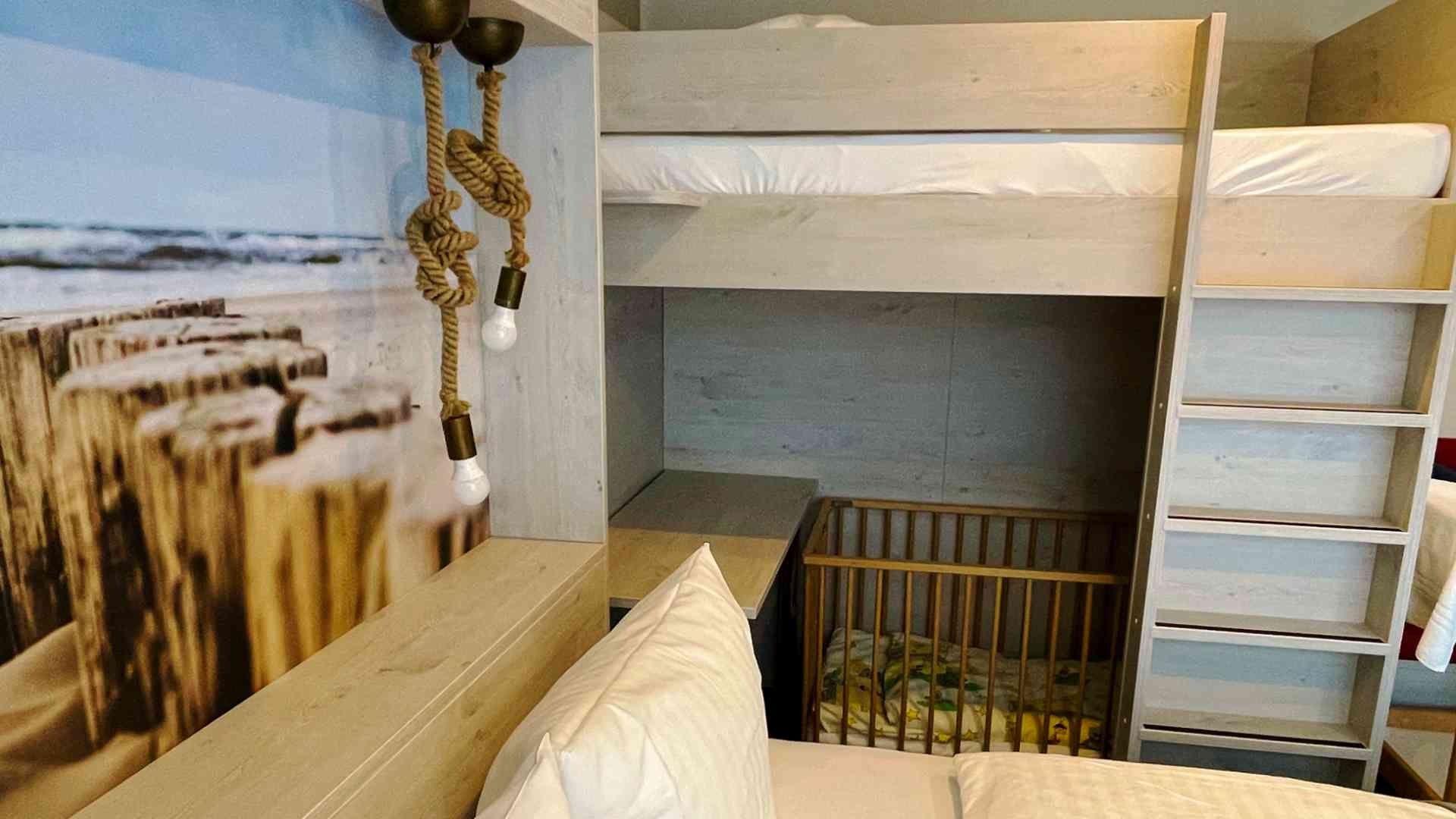 Blick über das Doppelbett hinweg auf das Etagenbett und das Gitterbett darunter