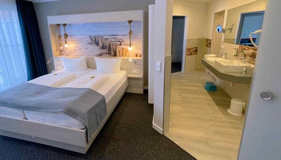 Blick auf das Doppelbett und das Durchgangsbad mit Doppelwaschbecken