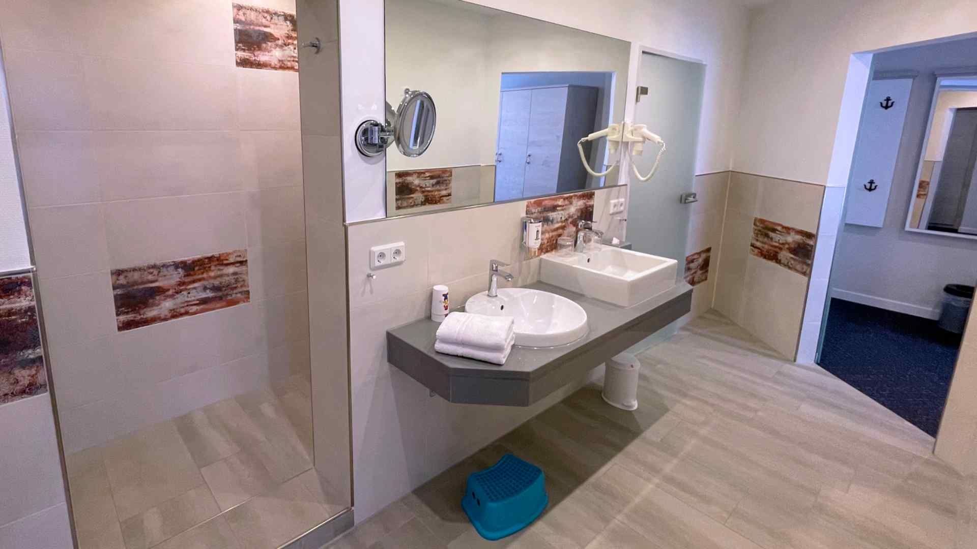 Blick in den Durchgang zur Dusche und auf den Doppelwaschtisch im Badezimmer in der Familien Suite Typ B1