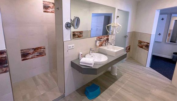 Blick in den Durchgang zur Dusche und auf den Doppelwaschtisch im Badezimmer in der Familien Suite Typ B1