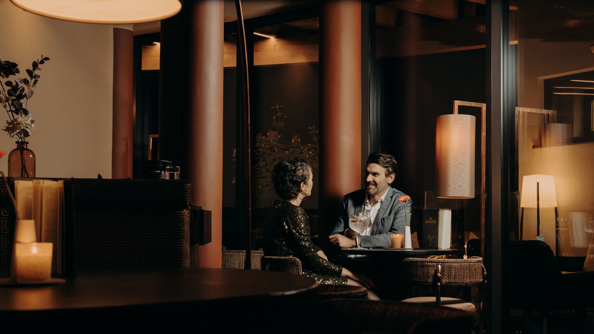 Paar sitzt am Abend in der stilvollen Hotelbar des Hotel Sonngastein bei Drinks in gemütlicher Atmosphäre.