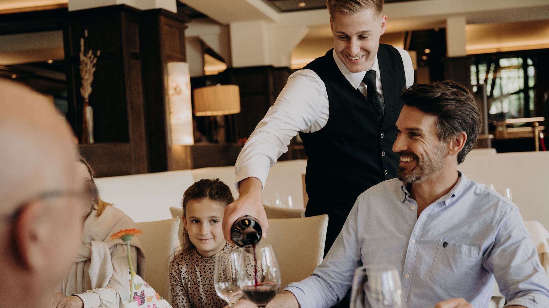 Familie beim Abendessen mit Service am Tisch im Hotel Sonngastein – Genuss und Familienurlaub in Gastein.