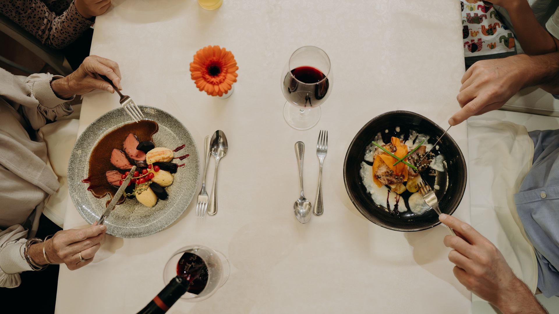 Familie beim Essen am Tisch aus der Vogelperspektive – Genuss und Familienurlaub im Hotel Sonngastein.