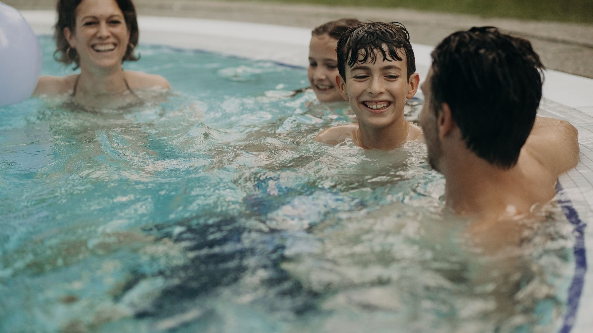 Familie im Außenpool des Hotel Sonngastein mit Wasserball – Badespaß und Familienurlaub in Gastein.