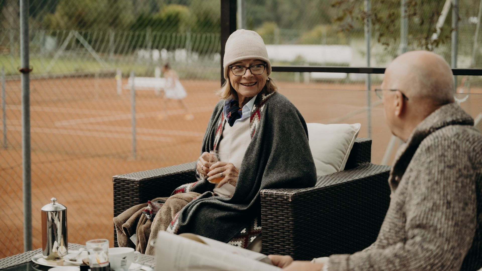 Großeltern auf der Terrasse mit Blick auf den Tennisplatz in Gastein – entspannte Urlaubsmomente im Hotel Sonngastein.