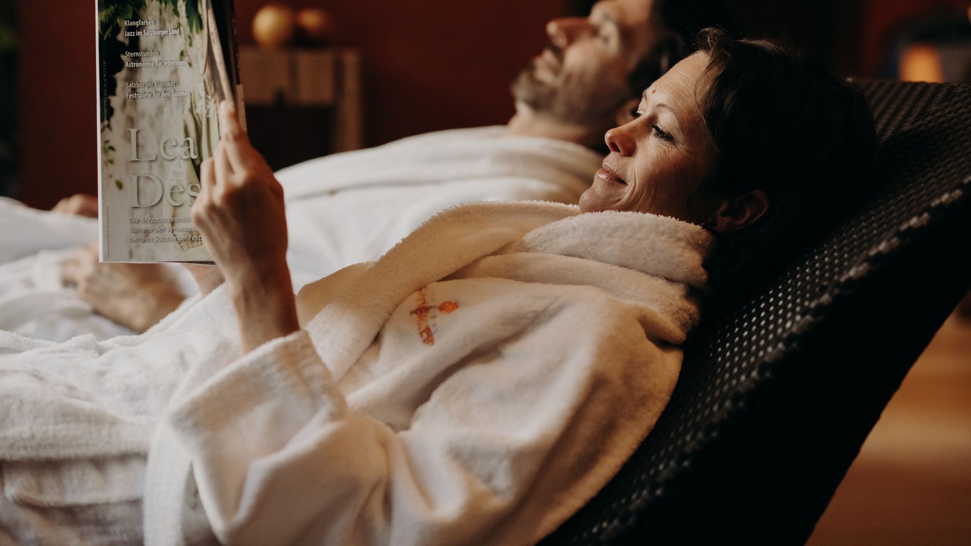 Paar entspannt im Spa-Ruheraum mit Bademantel und Magazin