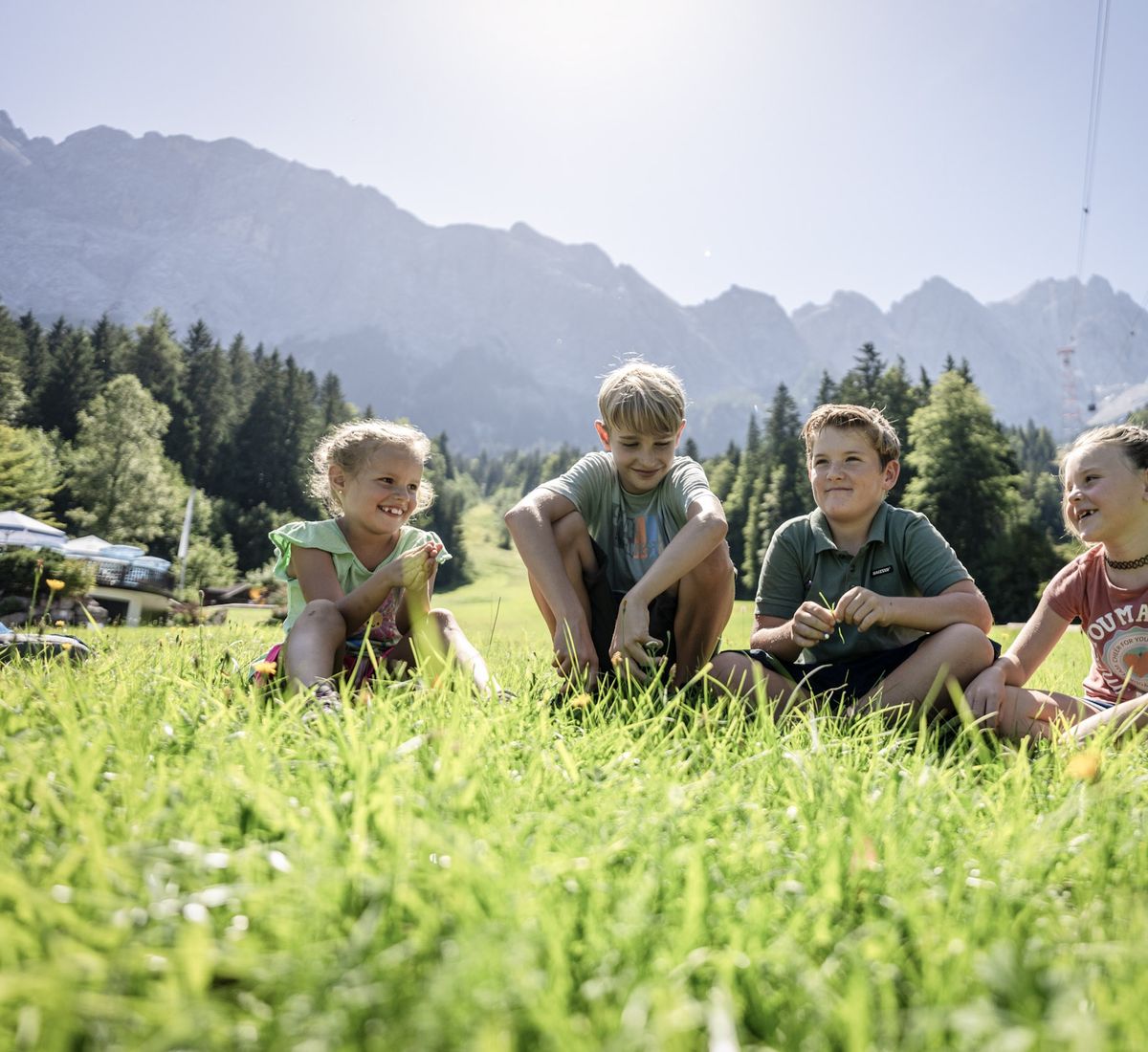 Kinder sitzen iin der Wiese an der Zugspitze