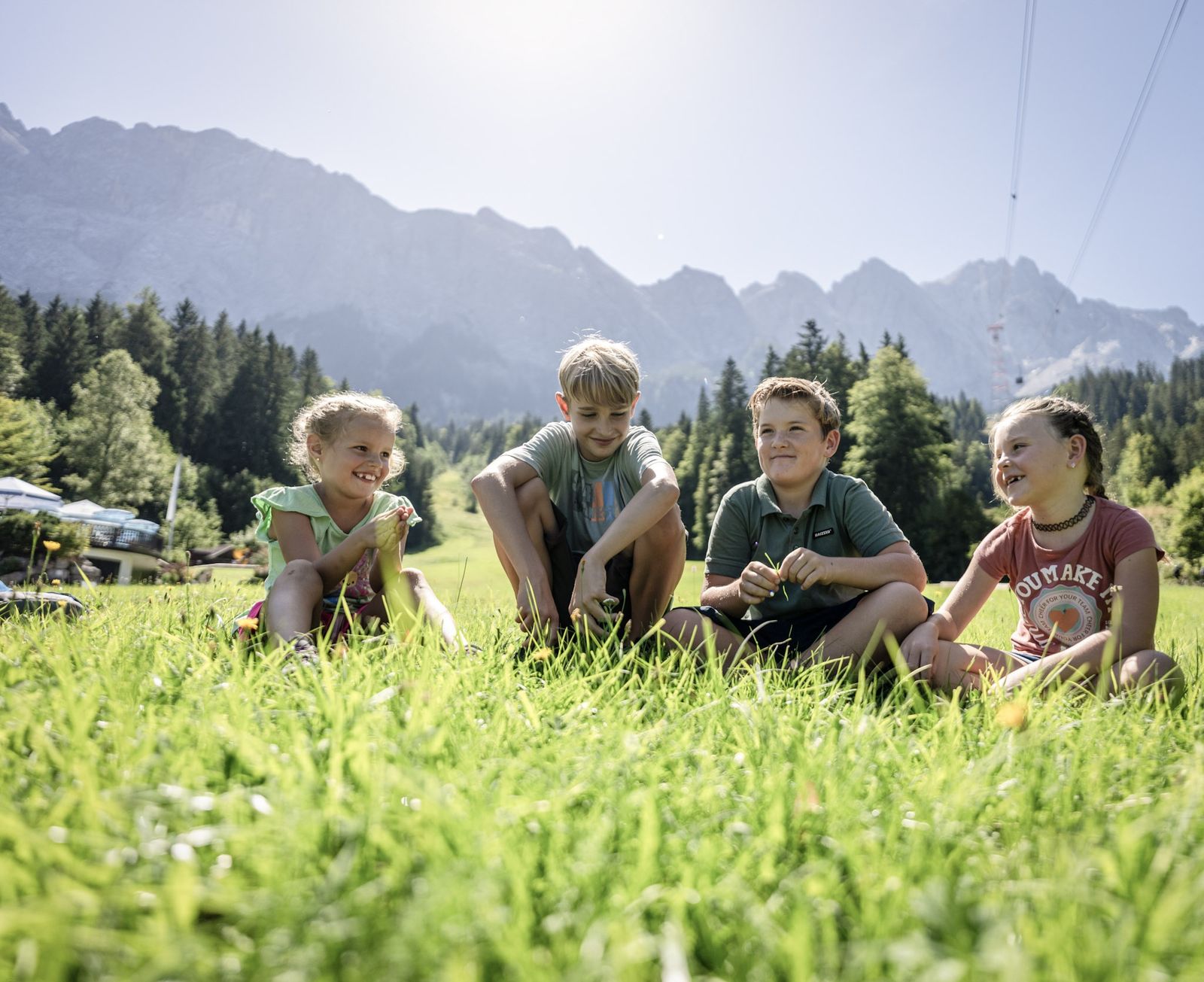 Kinder sitzen iin der Wiese an der Zugspitze
