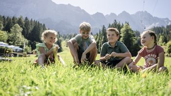 Kinder sitzen iin der Wiese an der Zugspitze