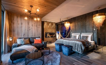 Die moderne und luxuriöse Golden-Sky-Suite mit kuscheligem Bett, liebevollen Details und großem Sofa zum entspannen.