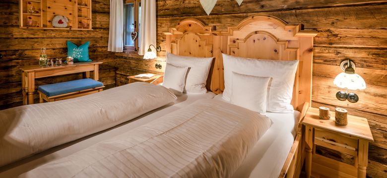 Uriges Schlafzimmer im Luxus-Chalet mit großem Holzbett und liebevollen Details.