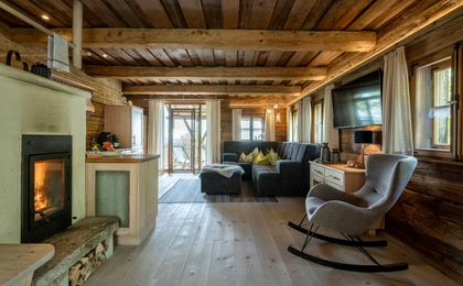 Der luxuriöse aber tradtitionell eingerichtete Wohnraum des Lieblings-Chalets mit großem Sofa, Kaminofen und offener Küche.