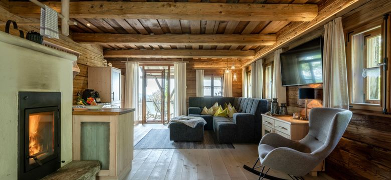 Der luxuriöse aber tradtitionell eingerichtete Wohnraum des Lieblings-Chalets mit großem Sofa, Kaminofen und offener Küche.