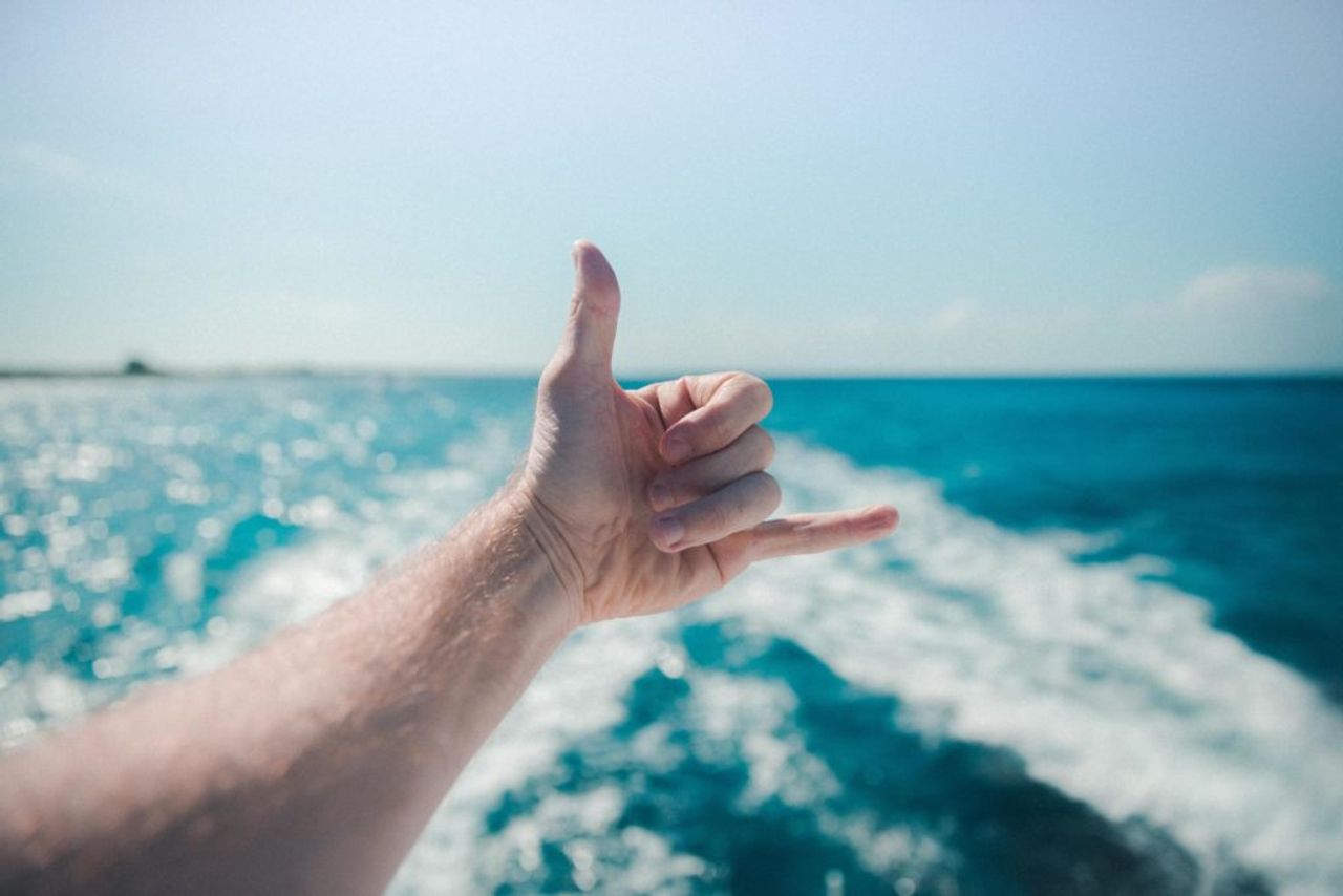 Foto von einer männlichen Hand im Surfergruß, während der Mann sich auf einer Bootsfahrt im Urlaub in Heringsdorf befindet