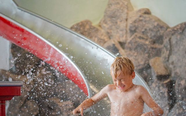 Junge auf der Rutsche im Kinderpool