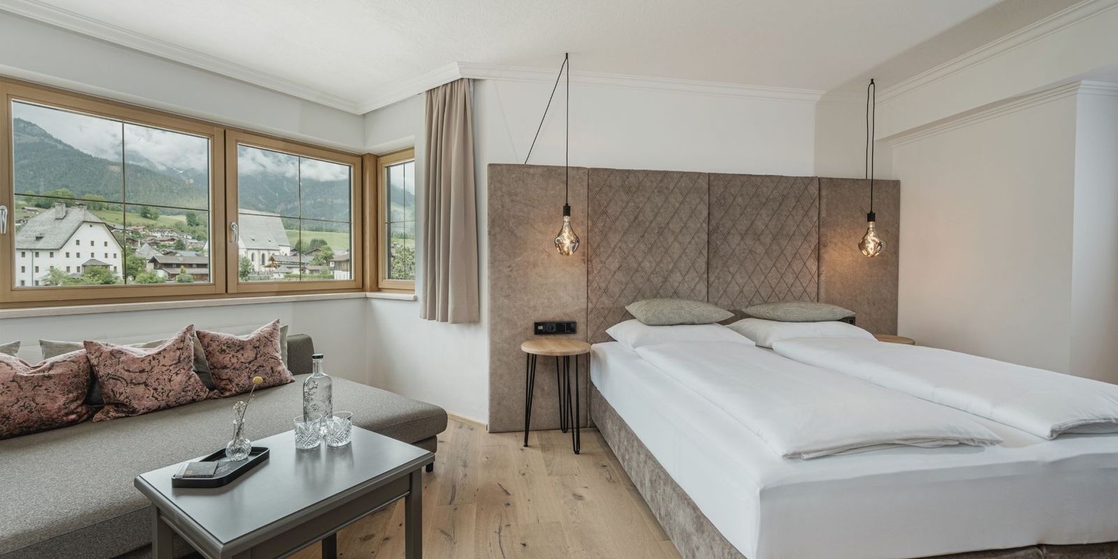 Modernes Zimmer im Hotel die HOCHKÖNIGIN in Maria Alm mit Blick auf das Dorf und die Berge, stilvollem Interieur und edlen Details.