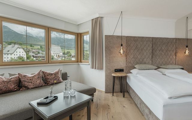 Modernes Zimmer im Hotel die HOCHKÖNIGIN in Maria Alm mit Blick auf das Dorf und die Berge, stilvollem Interieur und edlen Details.