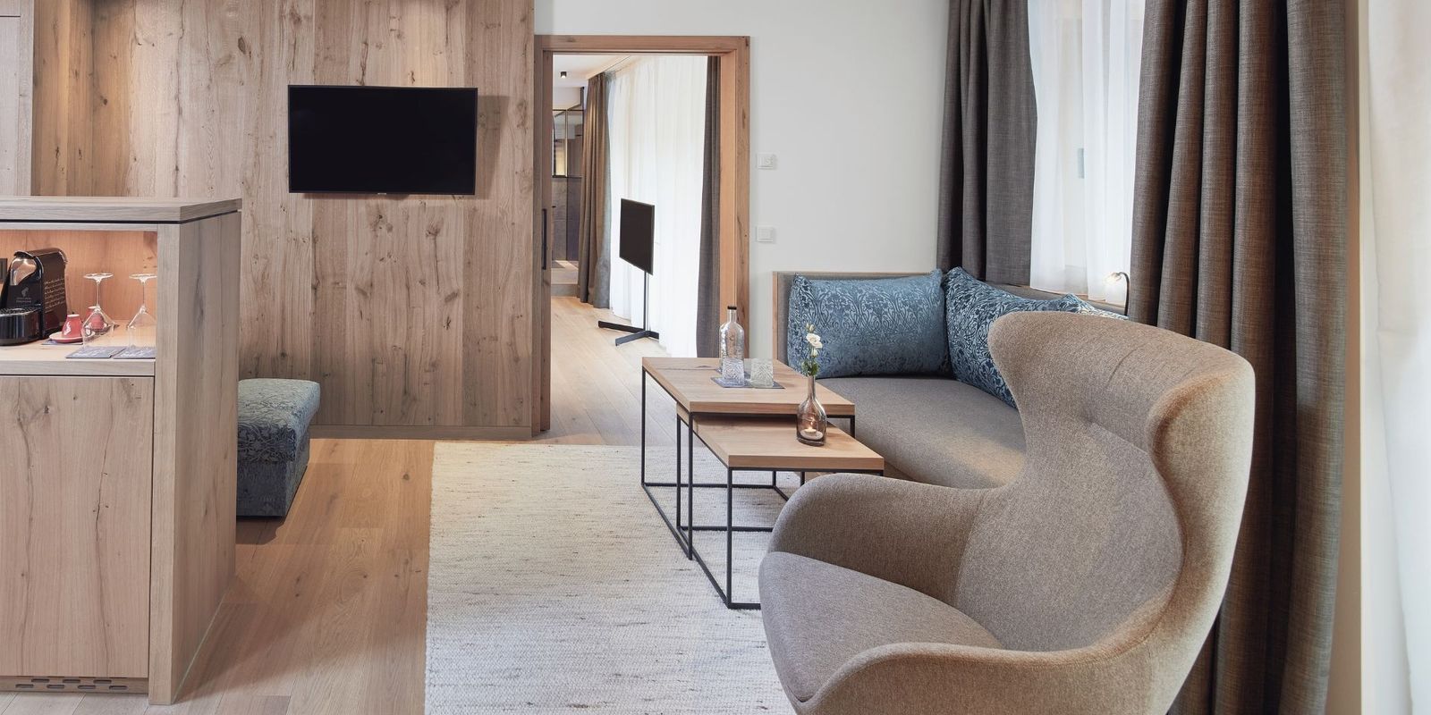 Helles Holz, elegante Stoffe und ein Hauch alpiner Eleganz: Der Wohnraum in der Suite der HOCHKÖNIGIN verbindet modernes Design mit behaglicher Wärme.Ein Ort zum Ankommen, Entspannen und Wohlfühlen in Maria Alm.