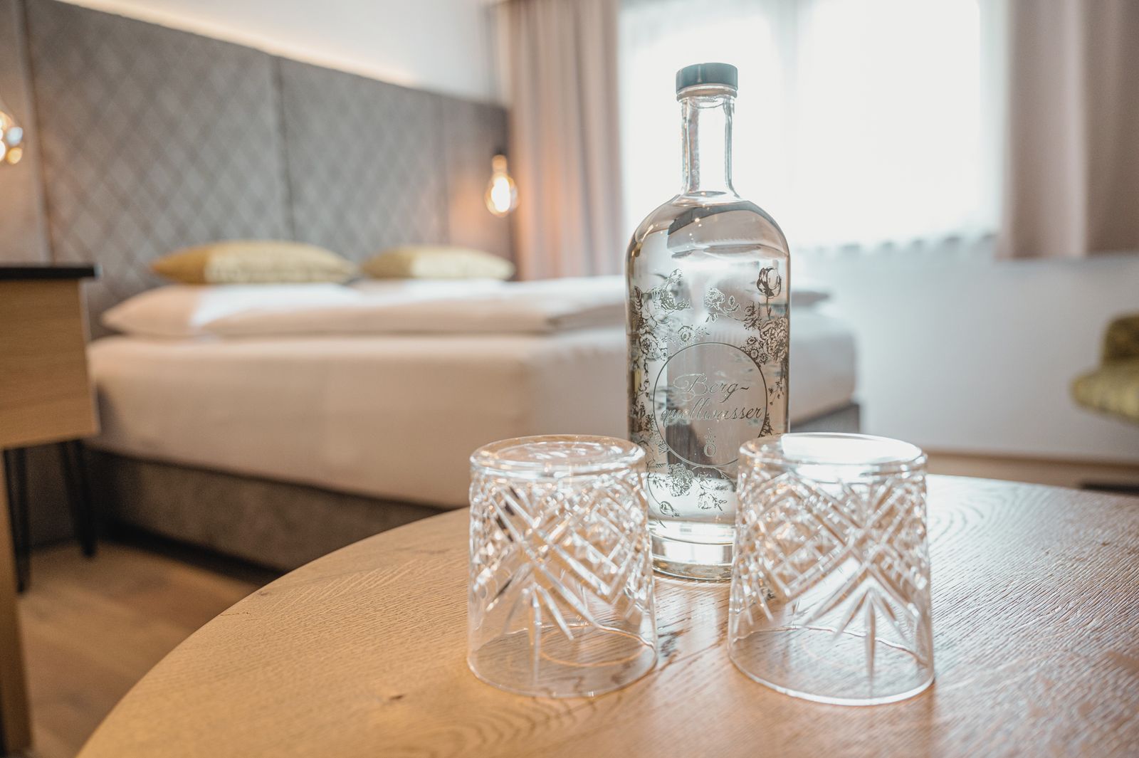 Zimmer im Hotel die HOCHKÖNIGIN mit Blick auf das Bett und Wasserflsche mit Kristallgläsern am Tisch