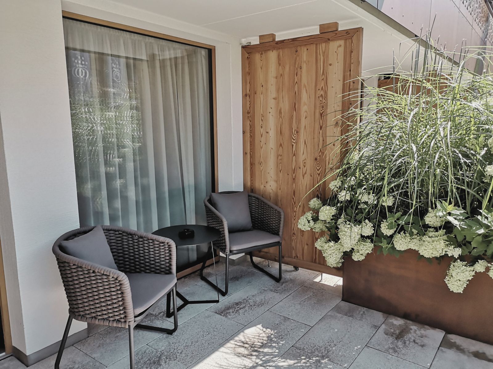 Überdachte Terrasse vom Hotelzimmer mit Sitzgruppe und Pflanzen