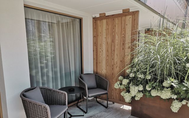 Überdachte Terrasse vom Hotelzimmer mit Sitzgruppe und Pflanzen